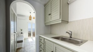 A modern kitchen with a large sink, light-colored cabinets, and a view to a balcony. - Phaedrus Living: Paros Cycladic Residences 7 (Piso Livadi)
