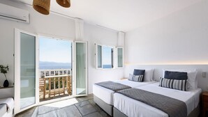 A bedroom with two beds, a balcony, and a view of the sea. - Phaedrus Living: Paros Cycladic Residences 7 (Piso Livadi)