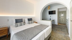 A bedroom with two beds, a desk, a TV, and a bathroom. - Phaedrus Living: Paros Cycladic Residences 8 (Piso Livadi)