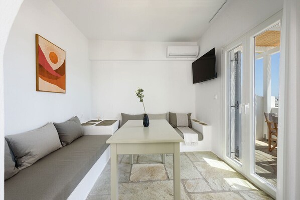 Una sala de estar moderna con un sofá, una mesa de comedor y un televisor montado en la pared.
