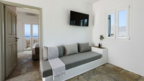 Un salon moderne avec un canapé, un téléviseur à écran plat et une vue sur la mer par la fenêtre.