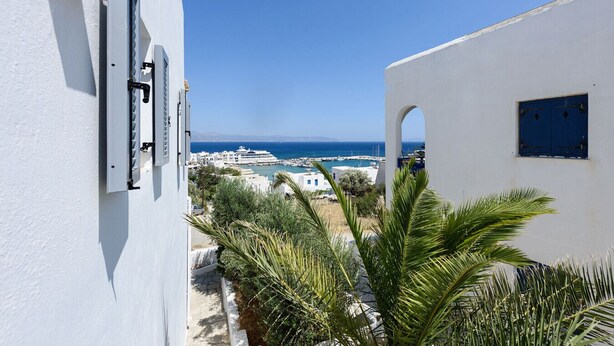 A white building with a view of the sea and a marina. - Phaedrus Living: Paros Cycladic Residences 11 (Piso Livadi)