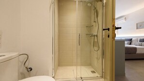 Une salle de bain moderne avec une douche à parois de verre, des toilettes et un porte-serviettes apparent.