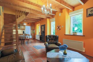 Una sala de estar con un sillón de cuero marrón, una escalera de madera y un comedor con mesa y sillas.