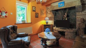 Una sala de estar con chimenea de piedra, mobiliario de cuero y televisor.