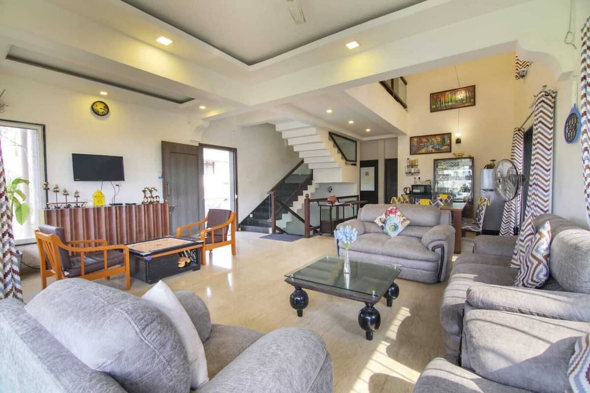 A spacious living room with a sofa set, a coffee table, and a TV mounted on the wall.