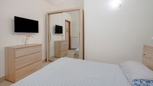 A bedroom with a bed, a dresser, a TV, and a mirror. - GuestHost - Comfortable 53 sqm apartment, perfect for 4 people, located on the ground floor of a building.The property is located in a residential area of ​​Monopoli, a few minutes from the historic center and the main city attractions, in an area fu (Monopoli)