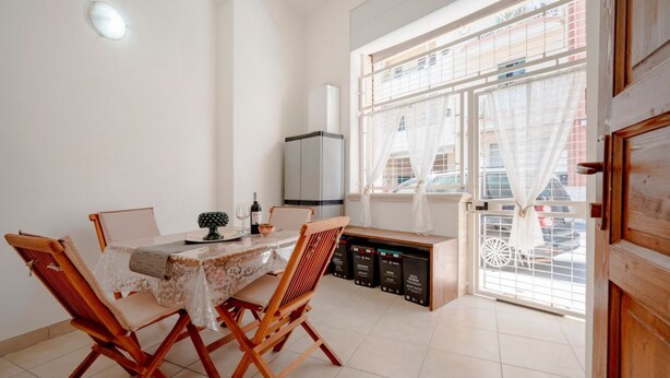 A dining area with a table, chairs, and a view through a window. - GuestHost - Comfortable 53 sqm apartment, perfect for 4 people, located on the ground floor of a building.The property is located in a residential area of ​​Monopoli, a few minutes from the historic center and the main city attractions, in an area fu (Monopoli)