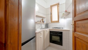 A compact kitchen with a refrigerator, oven, and a window above the sink. - GuestHost - Comfortable 53 sqm apartment, perfect for 4 people, located on the ground floor of a building.The property is located in a residential area of ​​Monopoli, a few minutes from the historic center and the main city attractions, in an area fu (Monopoli)