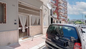 A building with a garage door, a satellite dish, and a car parked in front. - GuestHost - Comfortable 53 sqm apartment, perfect for 4 people, located on the ground floor of a building.The property is located in a residential area of ​​Monopoli, a few minutes from the historic center and the main city attractions, in an area fu (Monopoli)