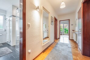 A hallway with a wooden floor, a white textured wall, and a door leading to a room with a window. - Apartment 'Lortz' with Private Terrace, Shared Garden and Wi-Fi (Cuxhaven)