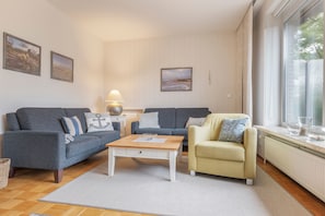 A living room with two sofas, a coffee table, and a chair. There are three framed pictures on the wall. - Apartment 'Lortz' with Private Terrace, Shared Garden and Wi-Fi (Cuxhaven)