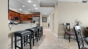 A kitchen with a bar area, wooden cabinets, and a tiled floor. - Two Bedroom with Pool Views (Destin)