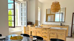 Una cocina moderna con armarios de madera, un ventanal grande y una mesa de comedor preparada para cuatro comensales.