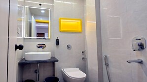 A modern bathroom with a white sink, a toilet, and a shower. - Stayinn Suites (Bhopal)
