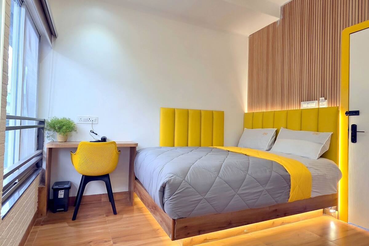 A bedroom with a bed, a desk, two chairs, and a window.