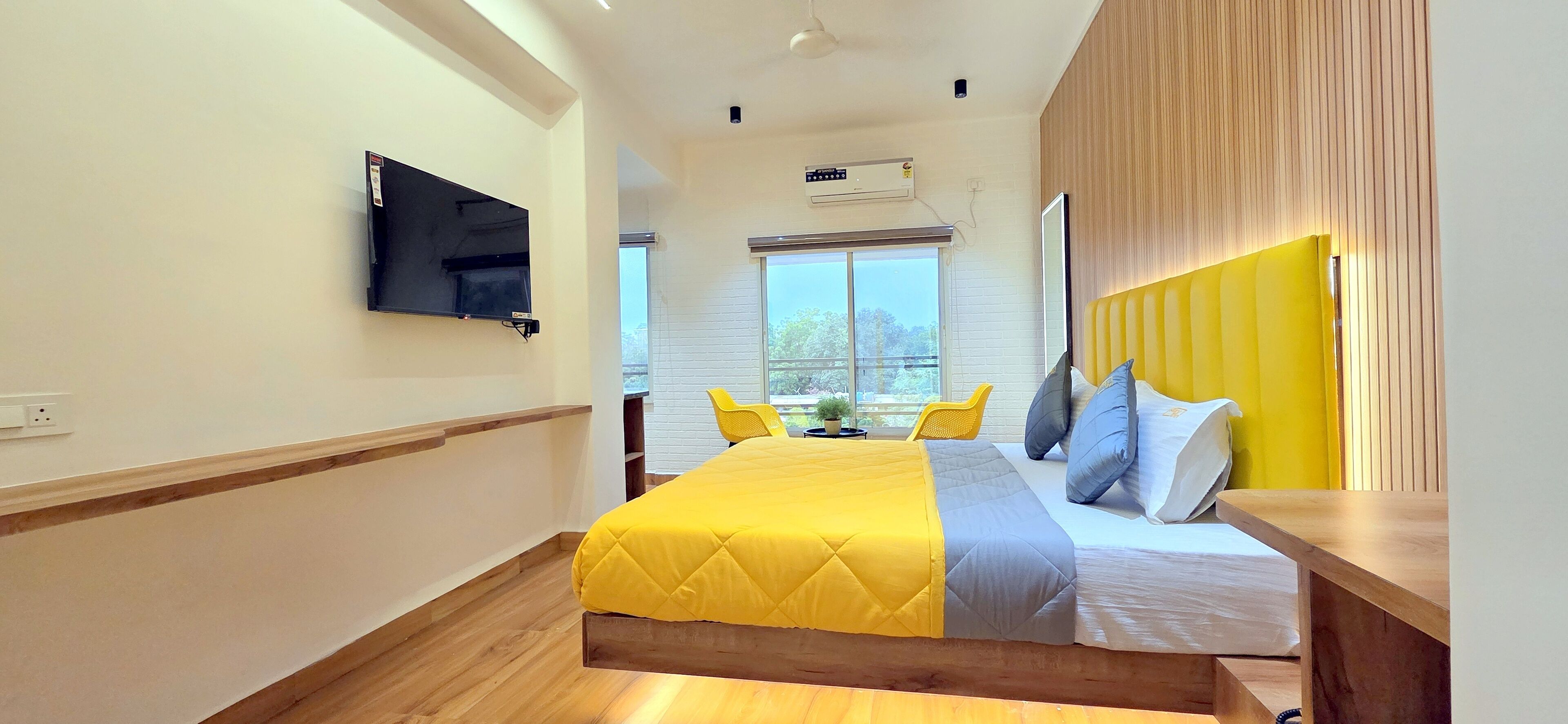Ein modernes Hotelzimmer mit Bett, Flachbildfernseher, Fenster mit Aussicht und Deckenventilator.