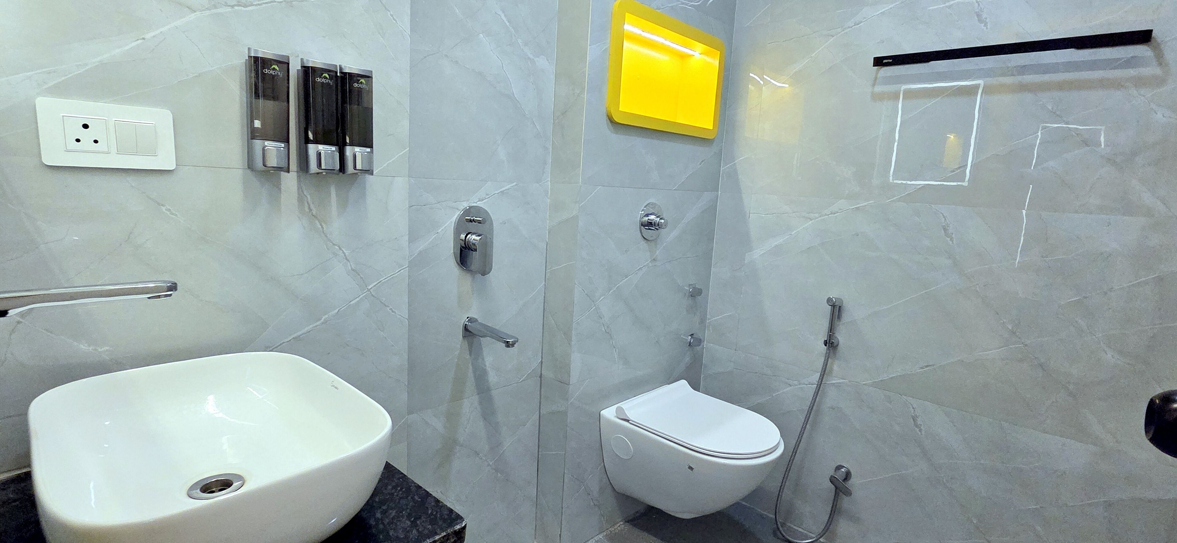 Une salle de bain moderne avec un lavabo, des toilettes et une douche, le tout de couleur blanche.