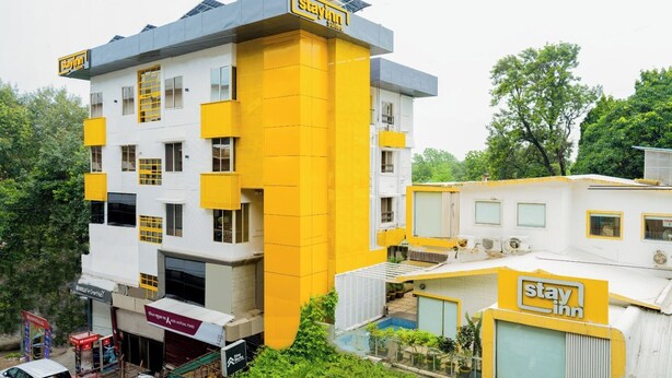 A multi-story hotel with a yellow and white facade, multiple balconies, and a rooftop terrace. - Stayinn Suites (Bhopal)