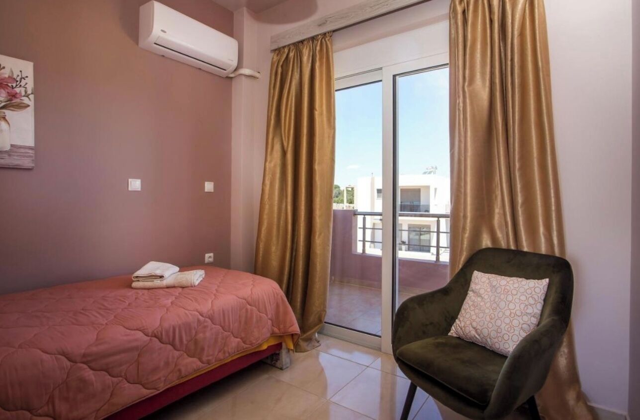 Une chambre à coucher comprenant un lit, une chaise et une porte-fenêtre coulissante donnant sur un balcon.