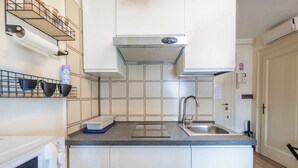 A compact kitchen with white cabinets, a stainless steel sink, a microwave, and a built-in oven.
