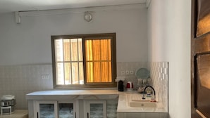 Eine kleine Küche mit Fenster, weißen Schränken, einer Spüle und einer Arbeitsplatte.