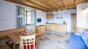Une pièce avec un plafond en bois, une table à manger ornée de pommes, un canapé et un coin cuisine.