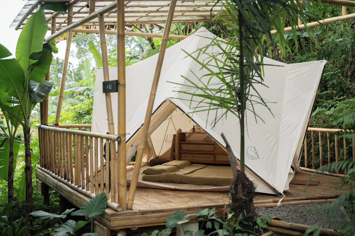 A bamboo structure with a tented sleeping area, surrounded by dense foliage.