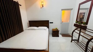 Une chambre à coucher avec un lit en bois, une table de chevet ornée d’une plante, un miroir et une porte donnant sur une vue agréable.