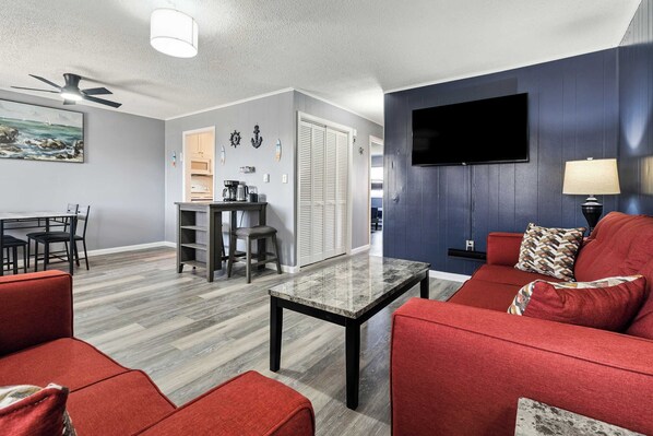 A modern living room with a red sofa, a coffee table, and a TV mounted on a dark wall.