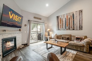 A living room with a fireplace, a sofa, a coffee table, and a large painting on the wall.