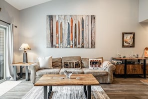 A living room with a sofa, coffee table, and a painting on the wall.