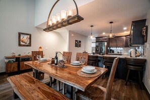 A dining area with a wooden table, chairs, and a chandelier.
