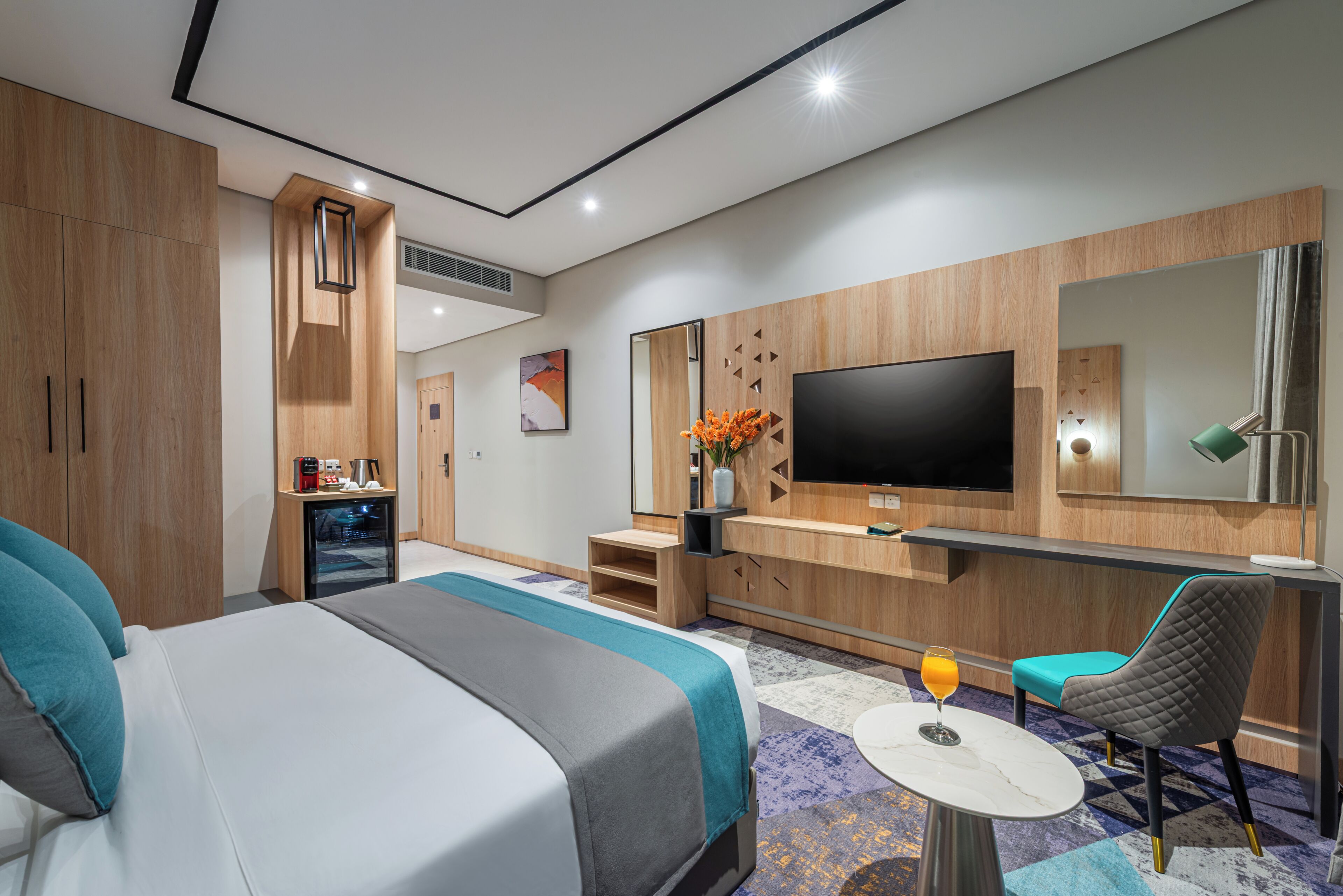 Ett modernt hotellrum med en stor säng, en TV, ett skrivbord och en stol.