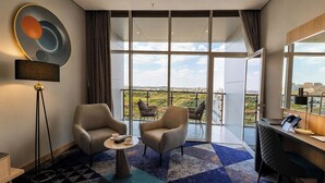 A modern hotel room with a large balcony, two armchairs, a desk, and a floor lamp. - Rhenium Hotel - Abha (Abha)