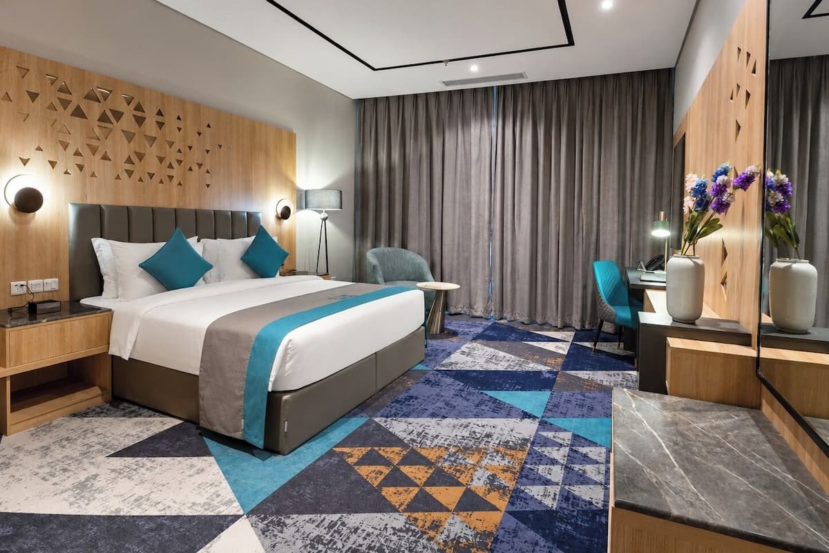 Una habitación de hotel moderna con una cama grande, un escritorio, una silla y un espejo.