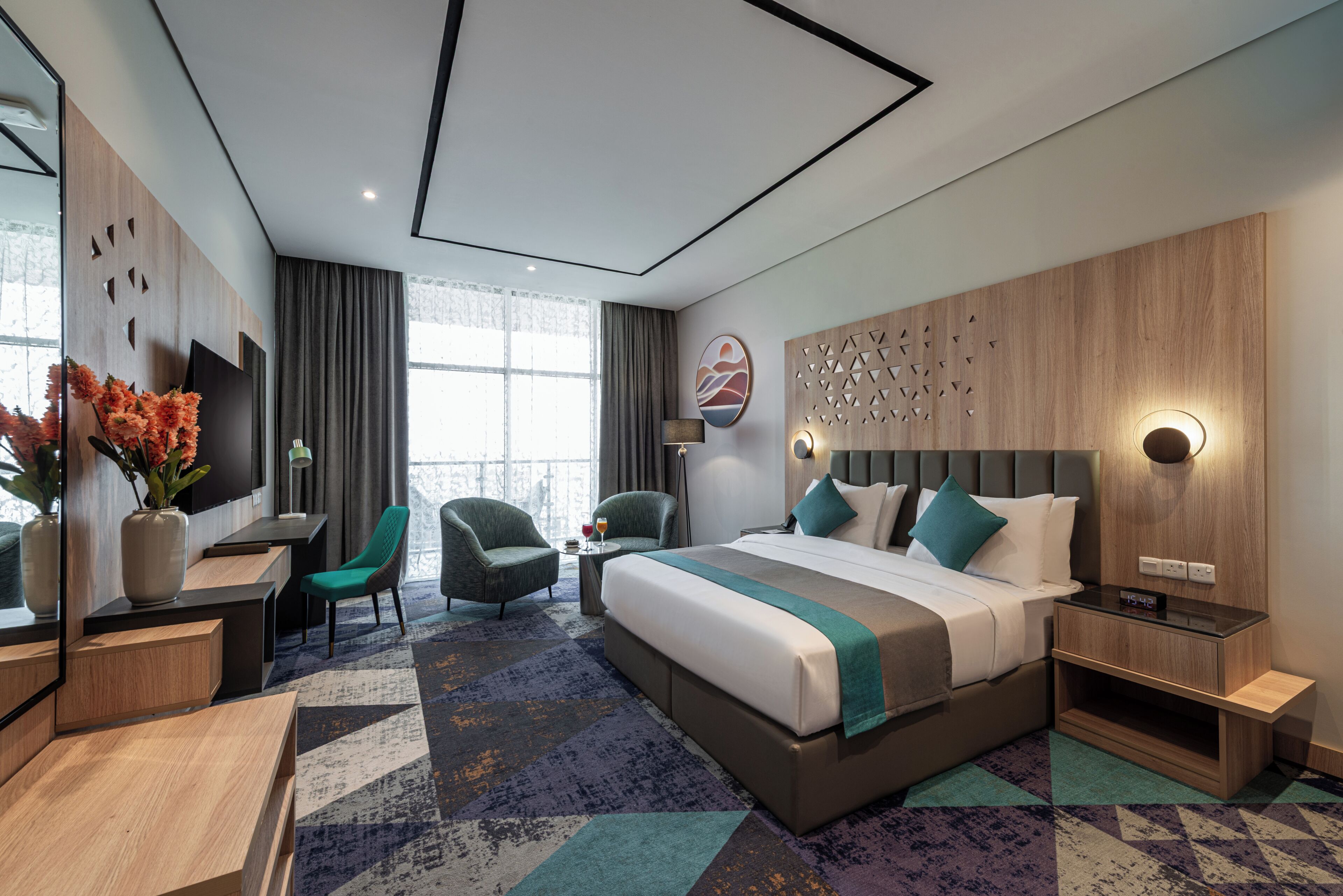 Et moderne hotelværelse med en stor seng, et skrivebord, en stol og et fjernsyn.
