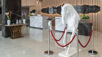 A reception desk with a 'Reception' sign, a white horse statue, and a red rope barrier.