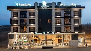 A multi-story hotel with balconies, a central entrance, and signage indicating it is a hotel by AlQasr. - Rhenium Hotel - Abha (Abha)