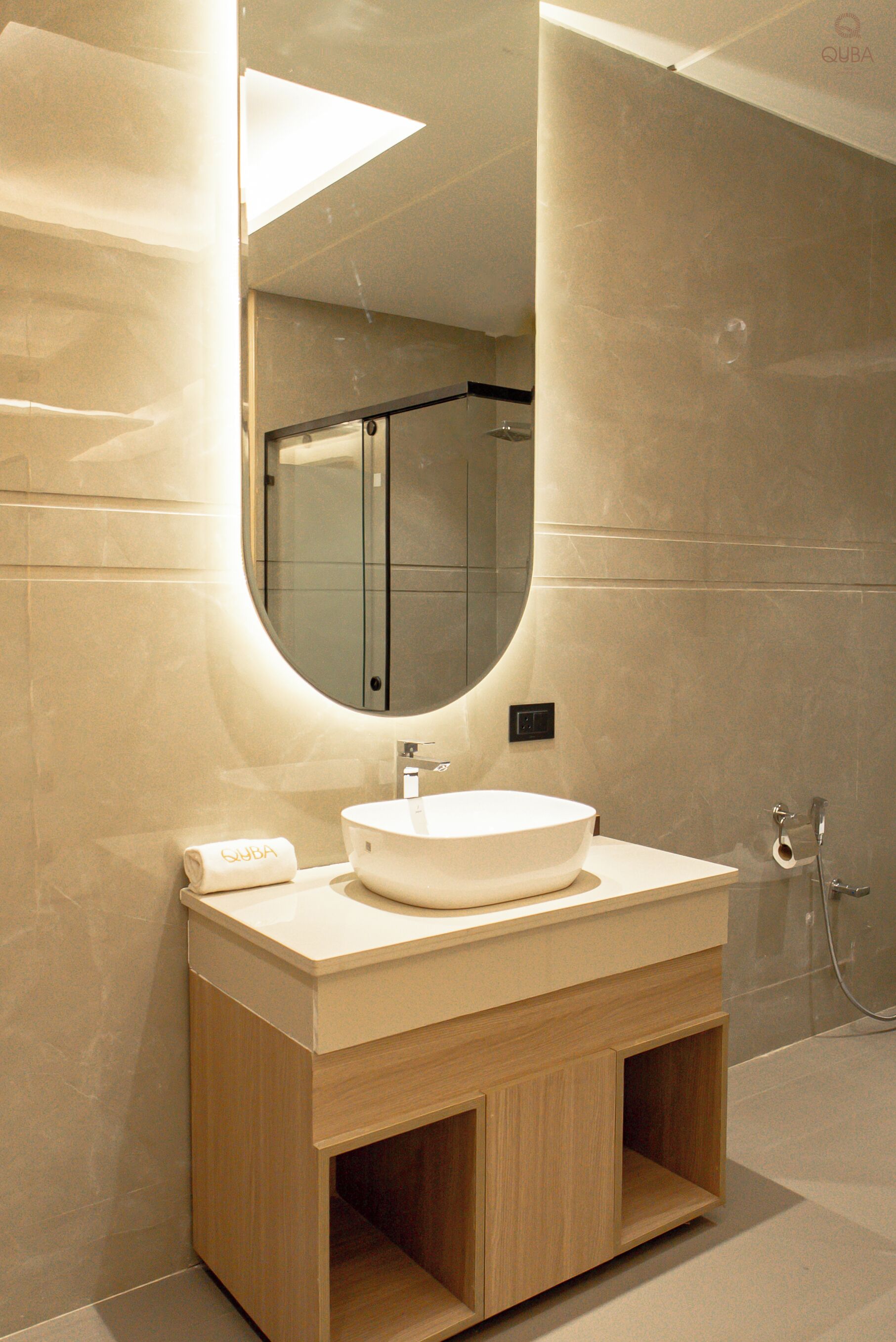 Un baño moderno con un espejo grande, un lavabo redondo y una zona de ducha.