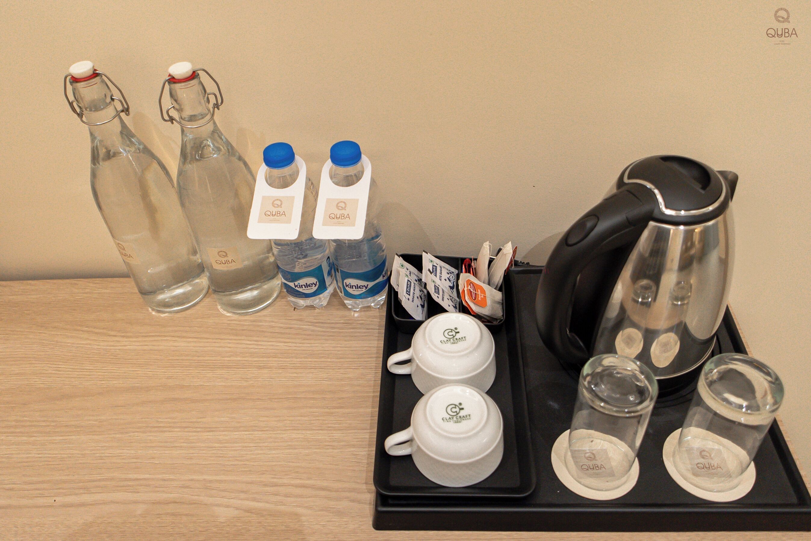 Un plateau avec une cafetière, deux tasses, deux verres et deux bouteilles d’eau.