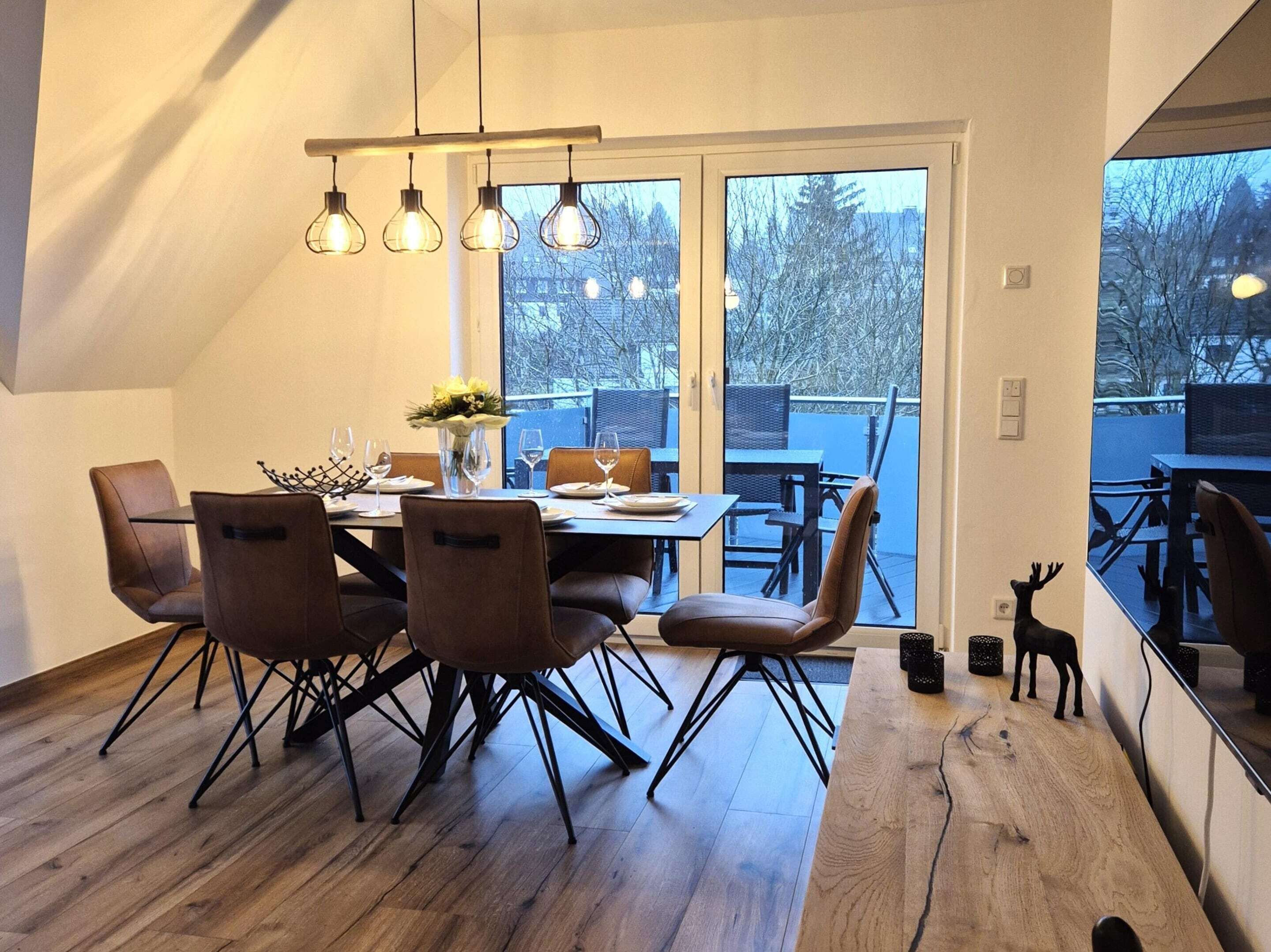 A dining area with a wooden table, six chairs, and a chandelier.