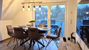 A dining area with a wooden table, six chairs, and a chandelier.