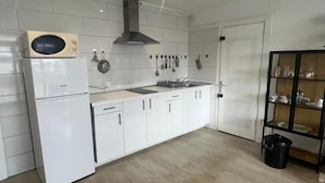 A modern kitchen with white cabinets, a built-in oven, a stainless steel range hood, and a black trash bin. - Apartment near beach for 2/4 ppl in Roses (Roses)