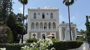 Un edificio histórico con fachada simétrica, ventanas en arco y una entrada central.