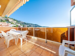 A balcony with a table and chairs, a view of a hillside town, and a clear blue sky.