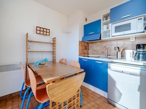 A compact kitchen with blue cabinets, a wooden dining table, and a microwave. - Studio for 6 with Wi-Fi, sea view (Roquebrune-Cap-Martin)
