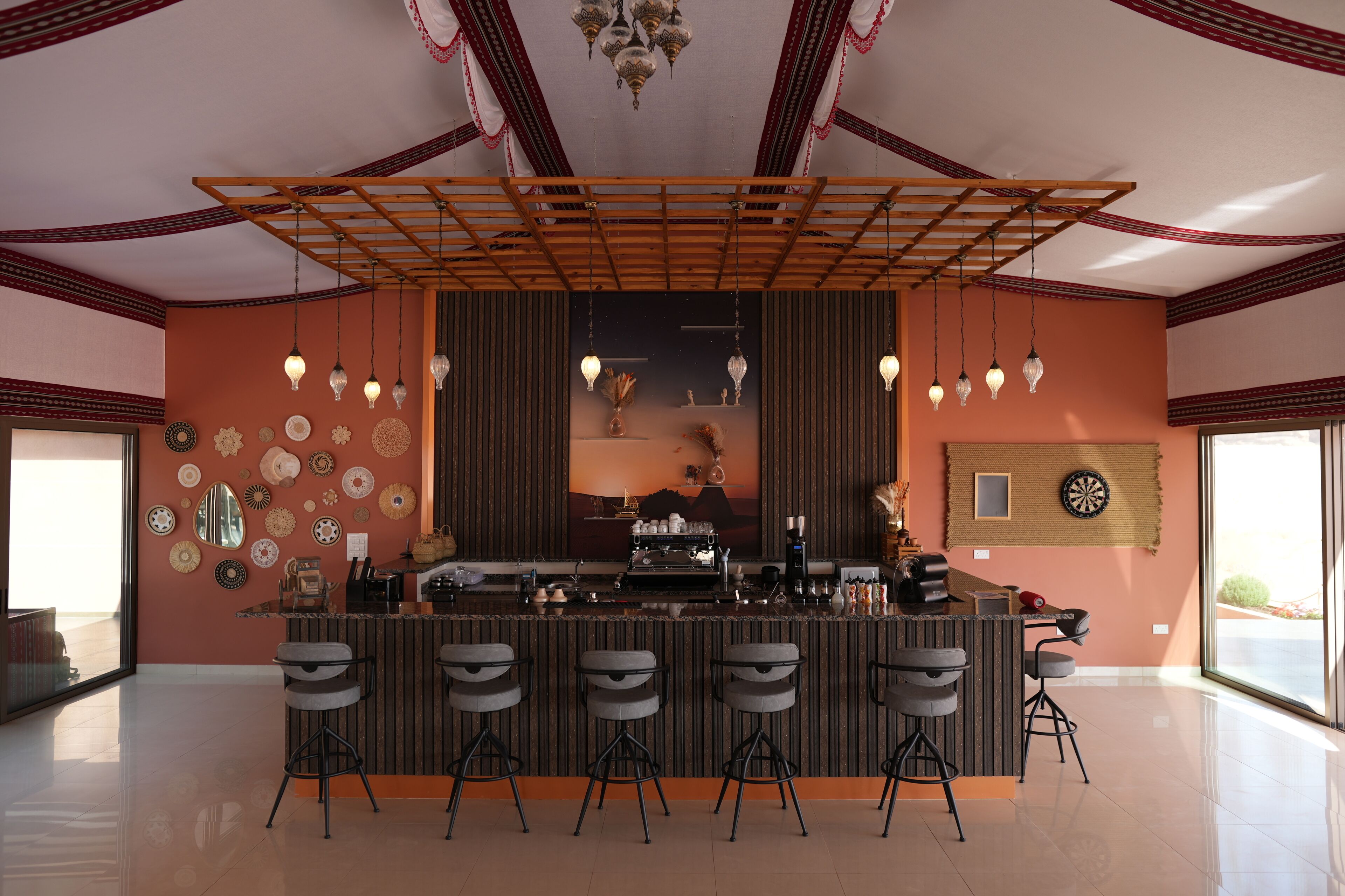 A modern kitchen with a bar area, featuring a central island with bar stools, decorative wall art, and a coffee machine.