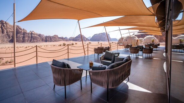 Un espacio al aire libre con mobiliario de mimbre y vista a un paisaje desértico.