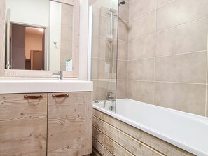 A bathroom with a wooden vanity, a mirror, a shower, and a bathtub.